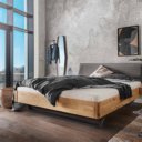 Tweepersoons houten bed met bruin stoffen hoofdbord